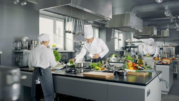 Two people making food on restaurant kitchen